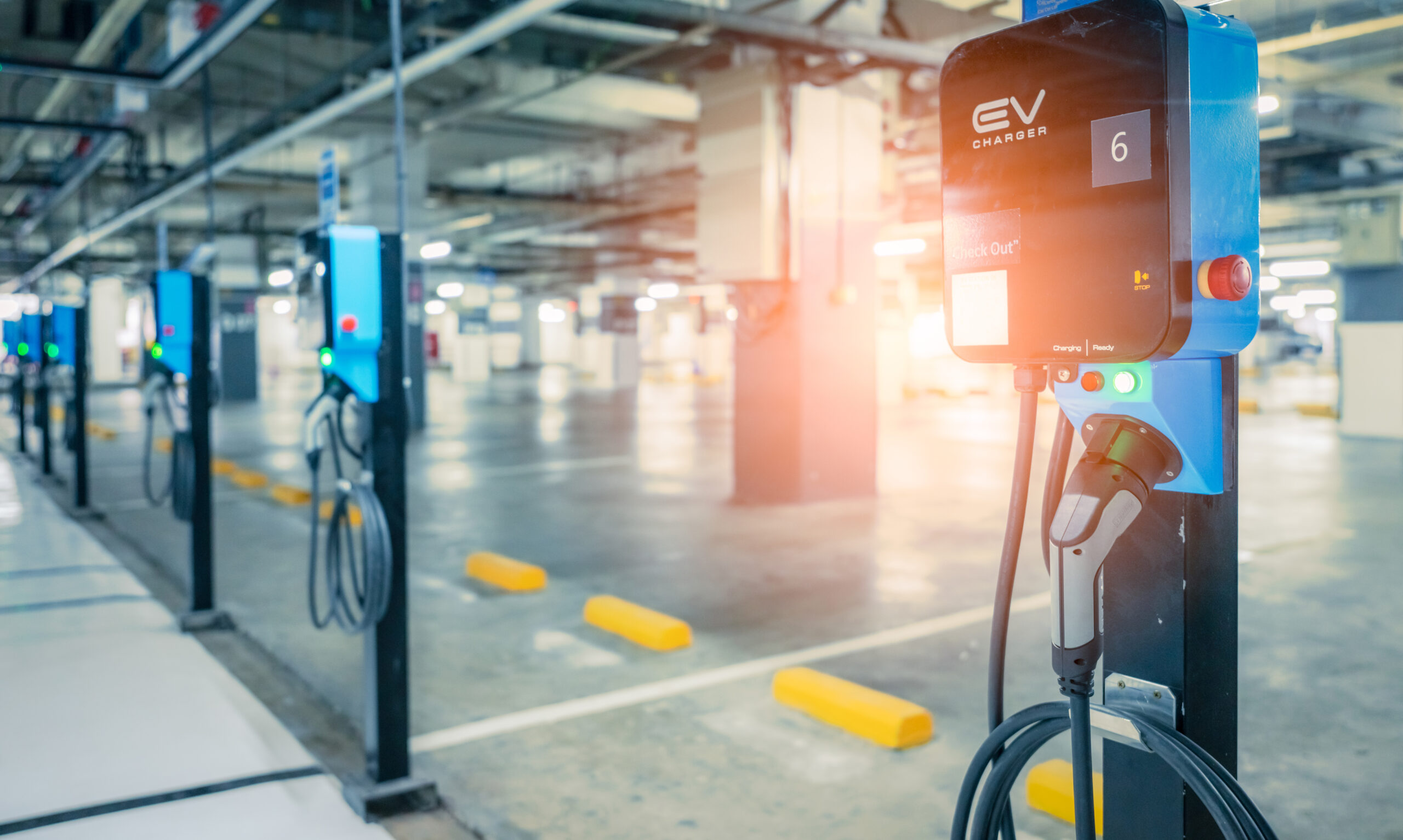 Electric car charging station for charge EV battery. Plug for vehicle with electric engine. EV charger. Clean energy. Charging point at car parking lot. Green power. Future transport technology.